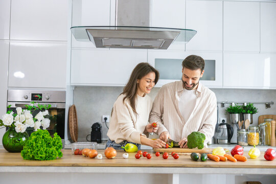 A couple engages in a caring and collaborative cooking experience, highlighting the joy of preparing food together in a kitchen.