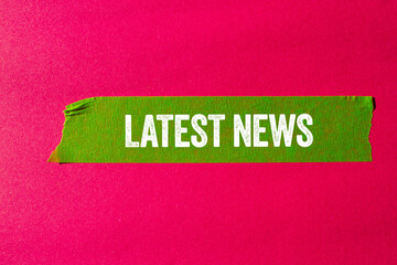 Latest news message written on ripped torn green paper tape on pink background. Conceptual latest news symbol. Copy space.