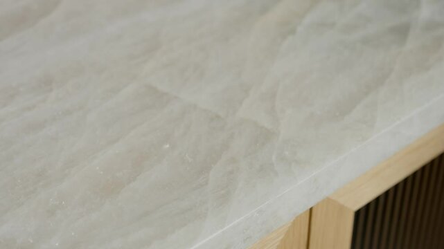 Close up of light colored, textured surface likely countertop or table. Surface has smooth marble like appearance with subtle variations in color and texture