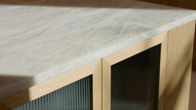 Close up view of kitchen countertop made of light colored marble or granite. Countertop has smooth, polished surface with subtle veining patterns