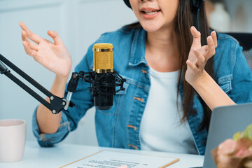 Host channel Asian influencer talking in broadcast streaming online wearing headset on social media live with script note, greeting listeners in life coaching or marketing at modern studio. Stratagem.