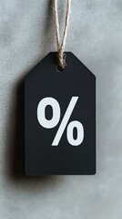 A matte black price tag featuring a prominent white discount symbol hangs against a light gray background