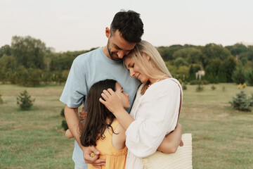 Fototapeta premium Mother, father, and daughter share a warm embrace in a tranquil setting.