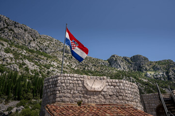 Croatian flag on old medieval fortress Sokol grad, in Konavle area, near Dubrovnik, famous touristic destination. The Croatian flag waves atop the medieval fortress Sokol Grad in the Konavle region