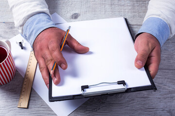 cup of  tea  and man hand  writing notebook  on wooden table