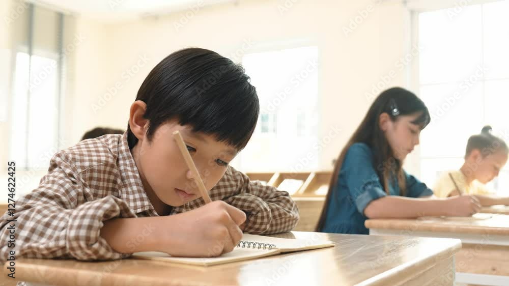 Poster close up of skilled asian student writing or taking a note during test. elementary student working o