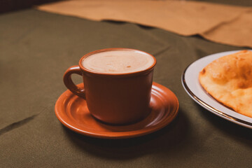 Coffee in a brown cup on a table with a tablecloth.