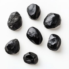 Seven shiny black mineral Shilajit resin stones isolated on a white surface.