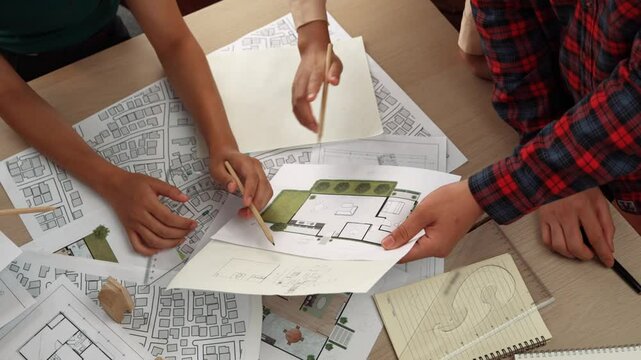 Smart architect and safety engineer discussion about building blueprint on table with architectural document, measurement tools and wooden block scatter around at modern office. Closeup. Delineation.