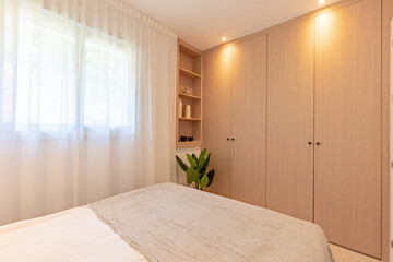 a small guest bedroom with fitted wooden closet and shelving in mediterranean hotel room