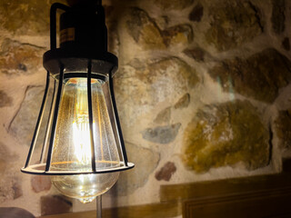 Rustic Hanging Lamp Illuminating a Textured Stone Wall..