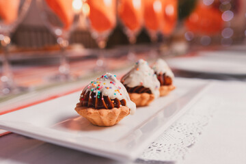 Small cookies with dulce de leche cream on top of a small rectangular plate.