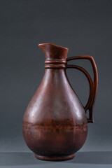 Handcrafted earthen pitcher displayed against a neutral background, showcasing traditional pottery techniques and craftsmanship in the art of ceramics