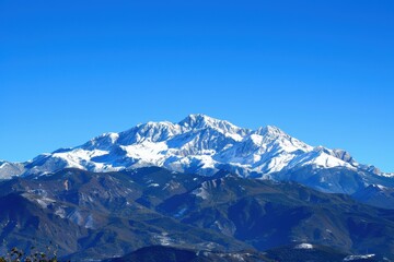 Obraz premium Majestic snow-capped mountains under a clear blue sky showcasing stunning natural beauty on a sunny day