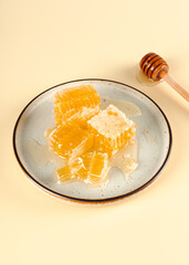 Honeycomb honey and liquid acacia flower honey on plate and honey stick on a yellow background. Organic natural food