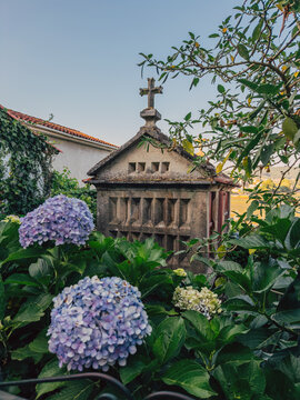 Stone structure with cross surrounded by lush garden with hydrangeas