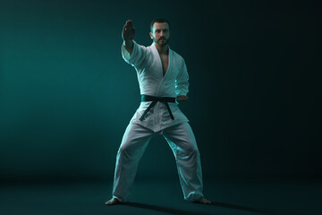 Man wearing uniform practicing karate in color lights