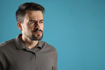 Sad man crying on light blue background, space for text