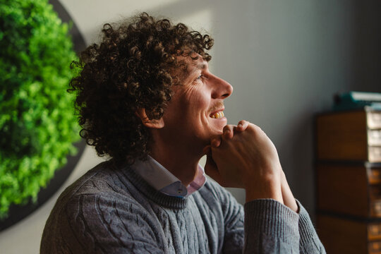 Curly-haired man against green wall reflecting sustainability - Powered by Adobe