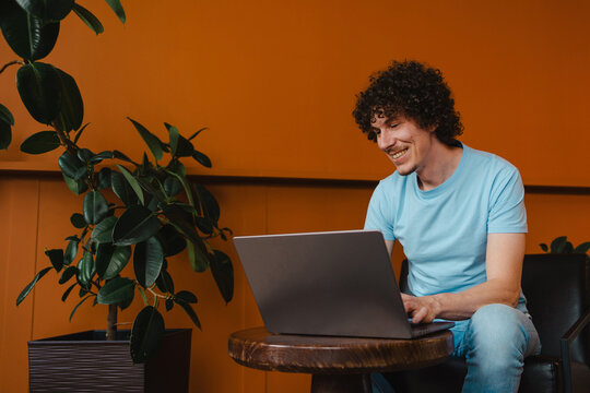 Young man with curly hair and laptop in a cozy setting