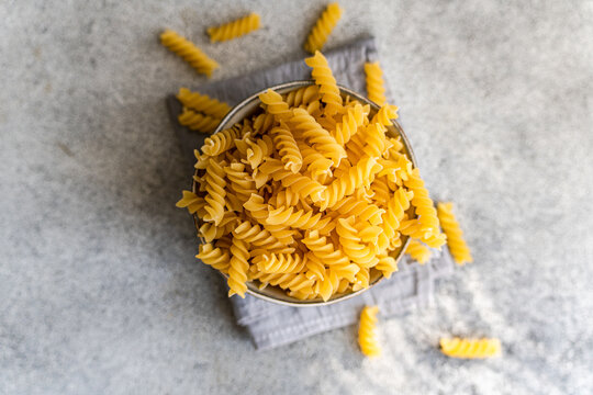 Close up of uncooked cavatappi pasta in a bowl on gray background