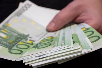 A close-up of a hand holding a bundle of euros, showcasing the texture and vibrant colors of the banknotes, symbolizing wealth and financial transactions.