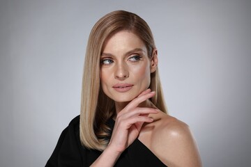 Portrait of beautiful woman with straight blonde hair on grey background