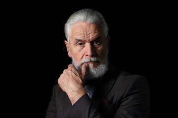 Obraz premium Portrait of serious senior man with silver beard on black background