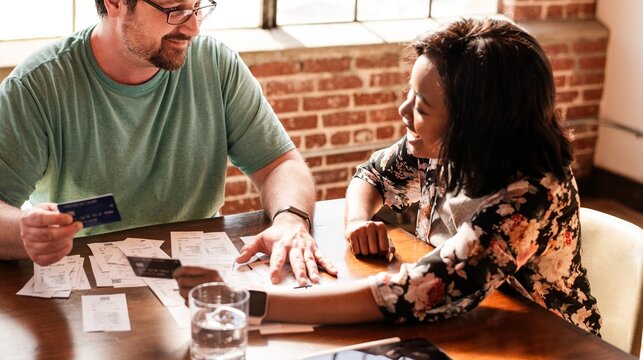 A Caucasian man and an African American woman team working together in the meeting. Diverse team discussing documents and credit cards in the meeting. Teamwork and collaboration are evident. - Powered by Adobe