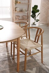 Stylish room with wooden table, chairs and houseplants. Interior design