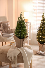 Small spruce trees decorated with Christmas lights indoors