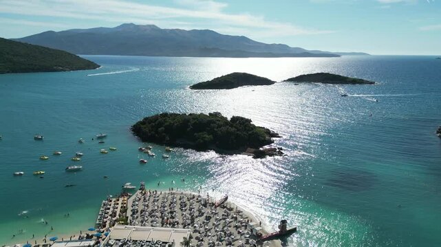 Aerial drone footage view of sea waves reaching shore in the coast Ksamil, beaches, islands and beautiful turqoise sea, Sarande, Adriatic Sea, Albania. Greek Corfu Island is at the background. 