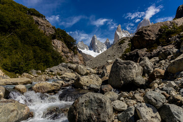 Fototapeta premium Fitz Roy sharp mountain peaks rise above a serene glacial lake, surrounded by rugged terrain snow-covered slopes in Patagonia, Argentina, El Chalten. Fitzroy mountain granite peak laguna de Los Tres