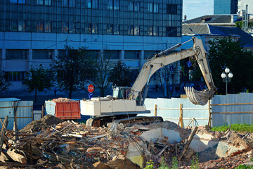 Excavator at demolition site clearing debris from demolished building. Construction machinery...