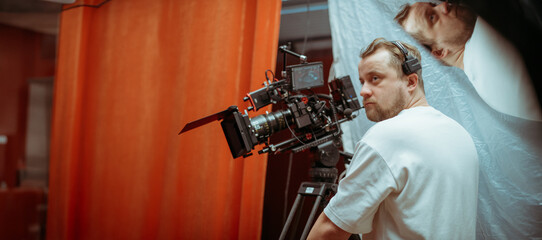 Director of photography with a camera in his hands on the set. Professional videographer at work on filming a movie, commercial or TV series. Filming process indoors, studio