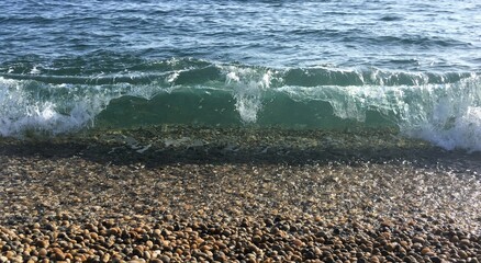 Crashing wave on pebble beach