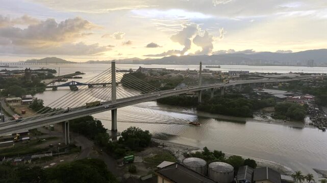 Butterworth, Penang, Malaysia HDR drone video over the Prai River with cars driving across modern bridge at sunset. Aerial view looking west towards ocean with Penang Island in the distance.