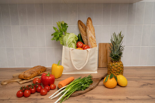 Fresh produce and bread in eco-friendly bag on wooden table