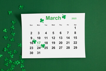 Top view of a paper calendar sheet with the selected date March 17, 2025 and a clover leaf and text "St. Patrick's Day" on a green background