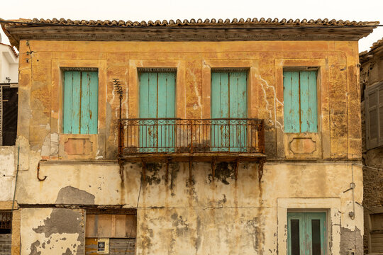abandoned building with balcony and peeling window shutters in Koroni, Peloponnese, Greece