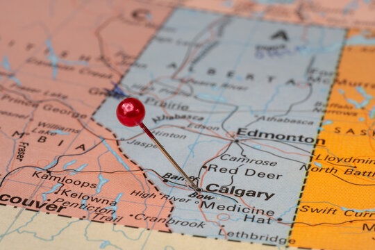 Tourist map of Alberta with a red pin stuck in next to Calgary. Colorful map
