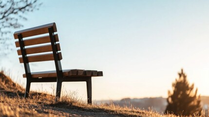 A wooden bench sits atop a grassy hill, facing the sunset, providing a tranquil spot for contemplation and solitude during golden hour