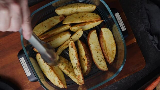 Cooking crispy air fryer potatoes as a side dish for diner or as an appetizer for a party.  Ingredients like Russet potatoes, paprika, onion powder, garlic powder sizzling up in an air fryer. 