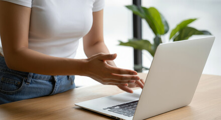 Fototapeta premium A woman is sitting at a desk with a laptop open in front of her