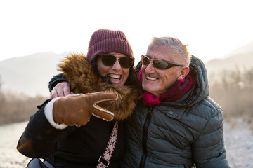 portrait of beautiful happy middle aged couple in love in winter clothes outdoors on a windy day