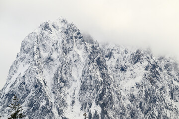 Cloud hangs on the rugged snow covrered peak of Mount index in winter