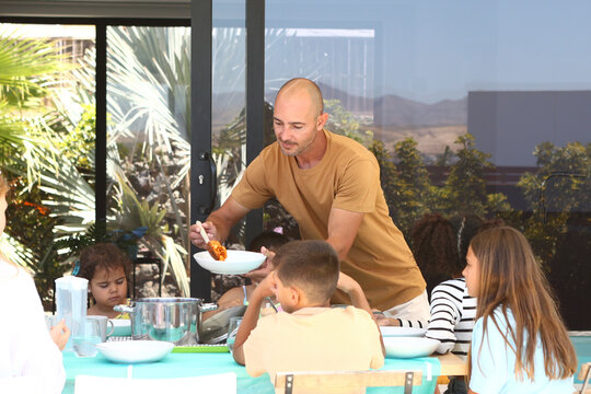 Family enjoying a meal together in a sunny outdoor setting - Powered by Adobe