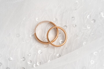 Two rose gold wedding rings on elegant white lace fabric