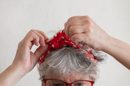 Senior woman tying red polka dot scarf in stylish hair accessory