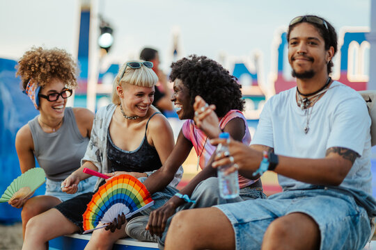 Young friends enjoying music festival, laughing and refreshing together